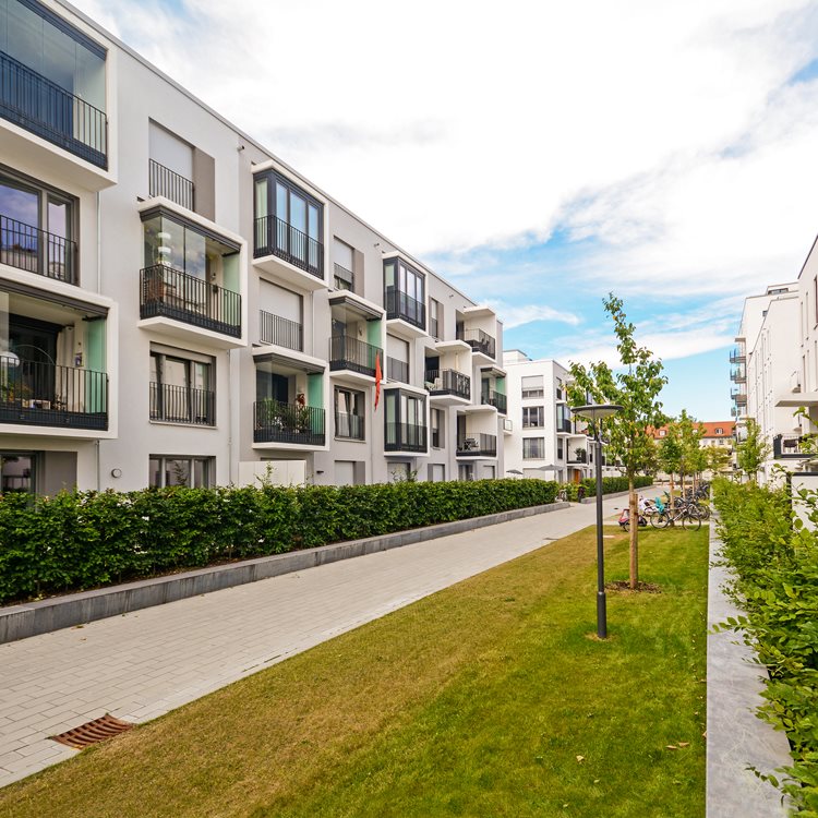 Modernt bostadsområde med flerfamiljshus, gångväg och grönska en solig dag