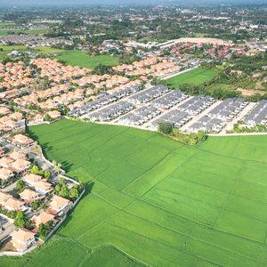Flygfoto över bostadsområde intill öppna grönområden och jordbruksmark