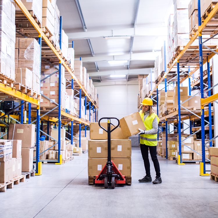 Lagerarbetare i logistiklager med höga hyllor och kartonger